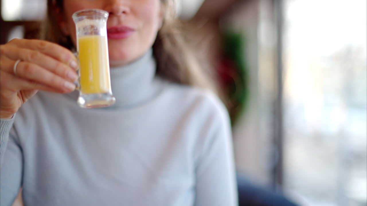 Woman drinking vitamin ginger immunity shot in a restaurant