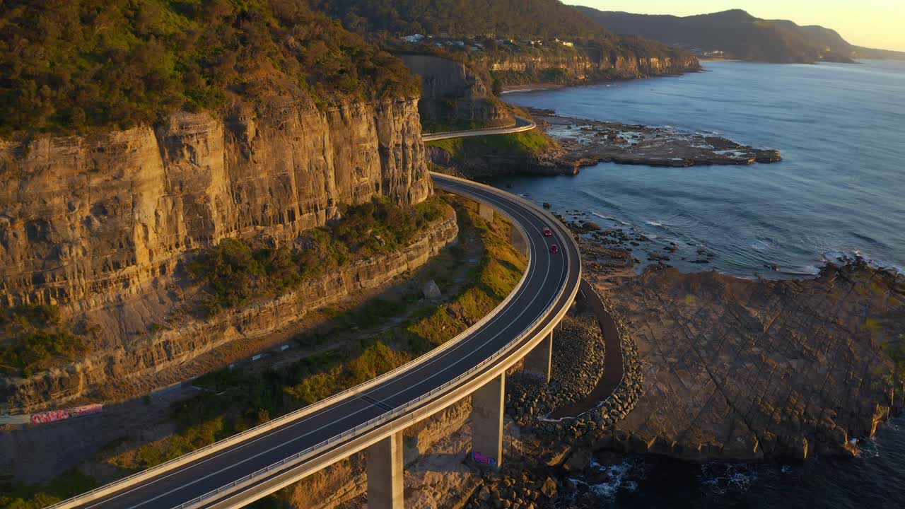 호주 뉴사우스웨일즈주 콜클리프(coalcliff)에서 햇살 가득한 일출에 바다 절벽 다리를 여행하는 자동차