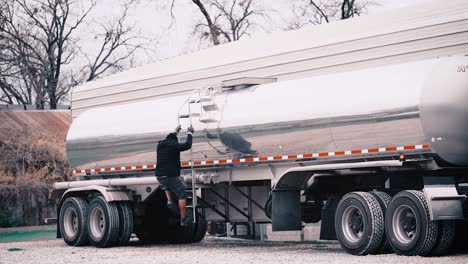mechanic climbing down ladder of fuel truck zoom out