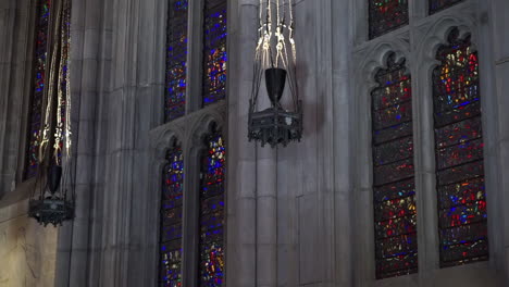 gothic stained glass windows and ornate hanging lamps in church interior
