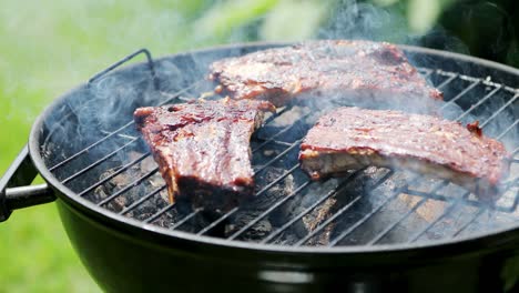 american barbecue - preparing beef ribs on charcoal grill