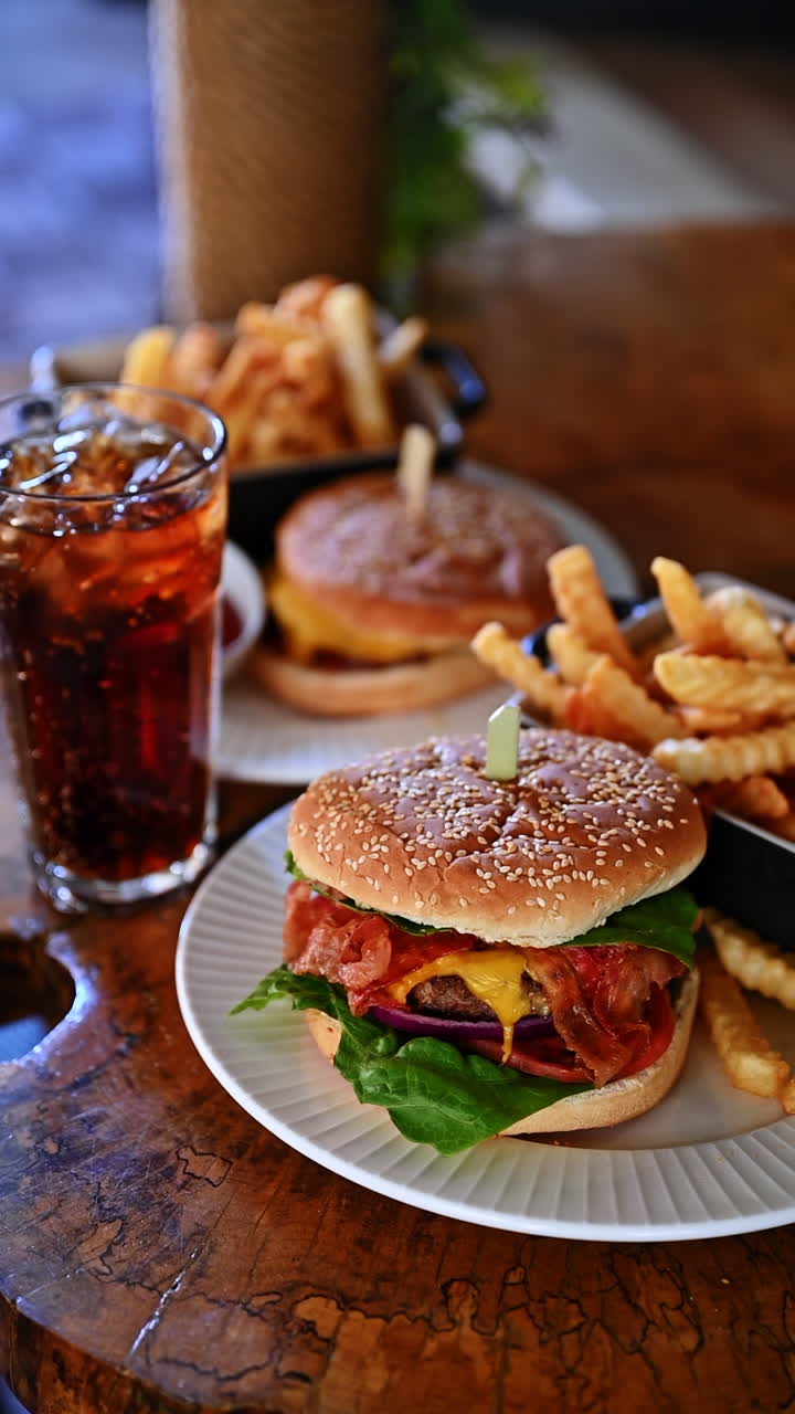 Cheeseburger with fries and cola in restaurant interior. Delicious cheeseburger with fries and soda on wooden table in cafe with blurred background