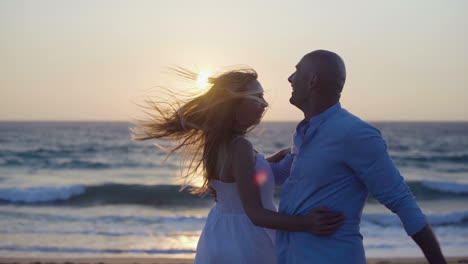 happy couple dancing on beach at sunset