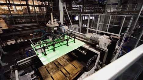 automated manufacturing plant removing green material from wooden pallets on swinging arm