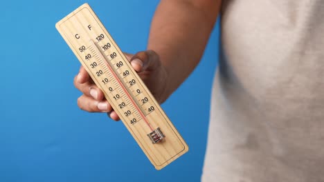 person holding a wooden thermometer