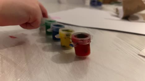 the child touches and takes away the paint containers. kids play at home. free time with the child. close-up