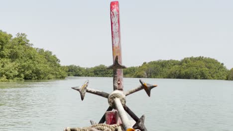 view of anchor resting on bow of boat vibrating travelling along mangrove forest river in sindh