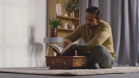 muslim man at home sitting and reciting from the quran 1