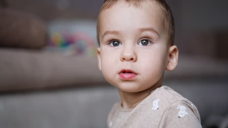 beautiful caucasian baby boy looking at camera and up. close up portrait. blurred backdrop.