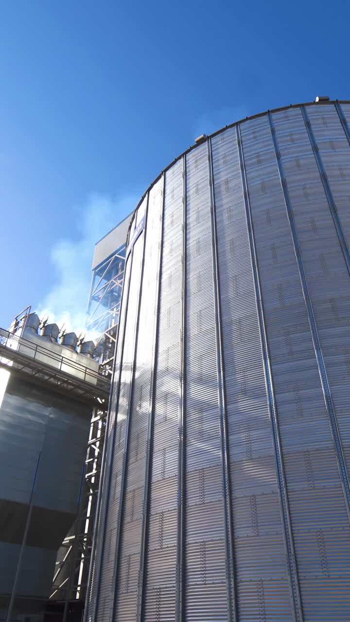 Metal grain elevator in agricultural zone. Agro manufacturing plant for processing drying cleaning and storage of agricultural products