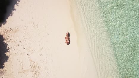 Spin-Aufnahmen-Eines-Braungebrannten-Mädchens,-Das-Am-Strand-Im-Sand-Liegt