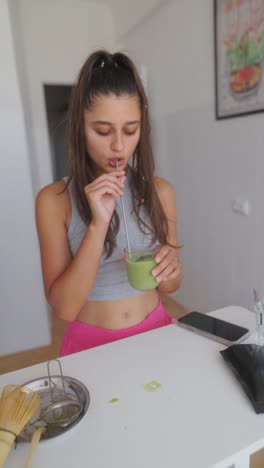 young woman preparing and drinking a green beverage