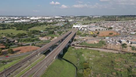 Die-Rotierende-Drohne-Fängt-Einen-Malerischen-Blick-Auf-Eine-Eisenbahnbrücke-In-Der-Nähe-Einer-Städtischen-Gemeinde-In-Johannesburg-Ein