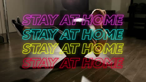 "animated neon 'stay at home' message over woman exercising during covid-19 quarantine."