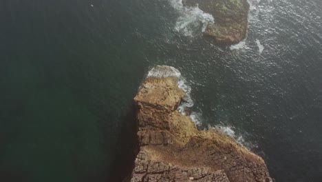 topdown-over-Rock-formation-with-foggy-clouds-in-atlantic-ocean