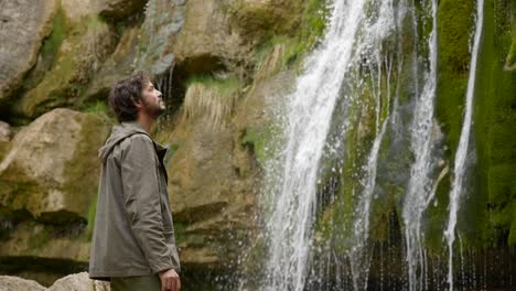 young male hiker in catalonia spain admiring and enjoying the waterfalls along the route of the seven pools - ruta dels set gorgs de campdevànol