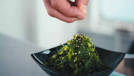 a chef adds seeds to a traditional japanese seaweed dish