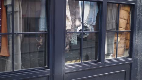 a storefront window display with clothes hanging in the window