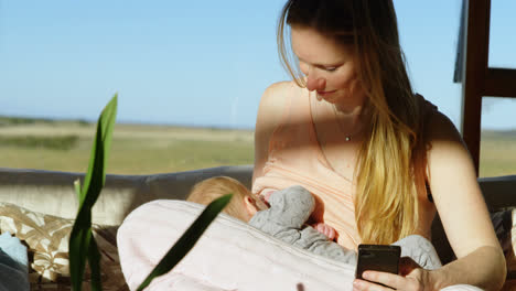 mother breast feeding her baby while using mobile phone 4k