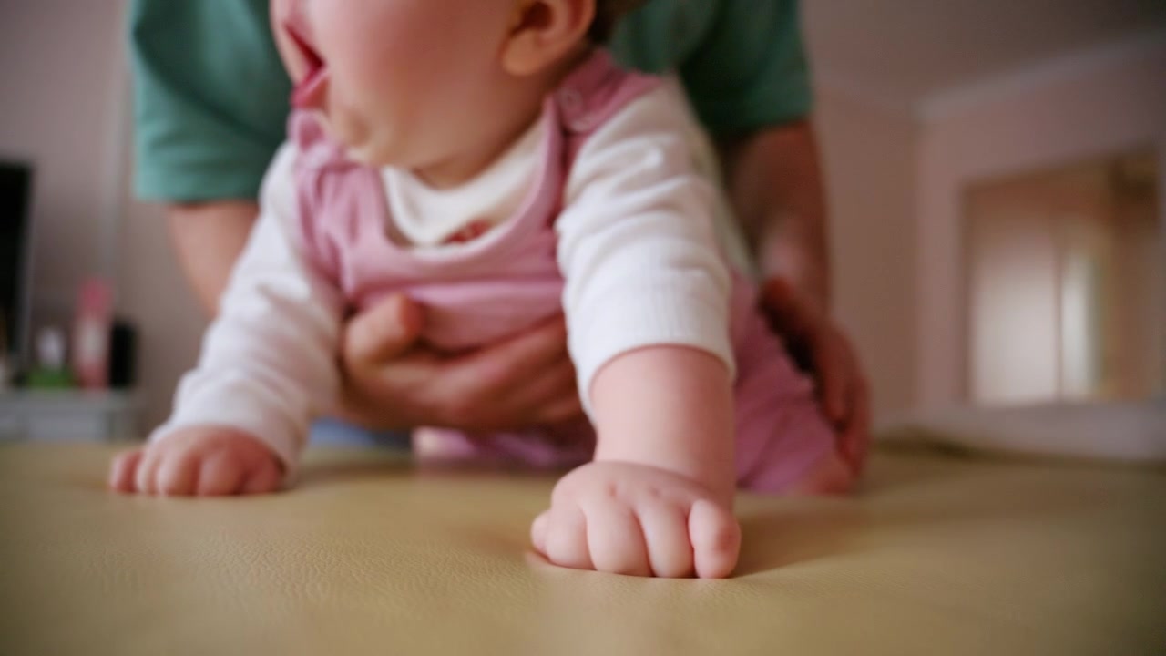 Primo piano di un assistente che si prende cura delicatamente di un neonato sdraiato su un fasciatoio imbottito, all'interno.