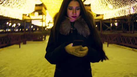 woman using phone at night in a winter city