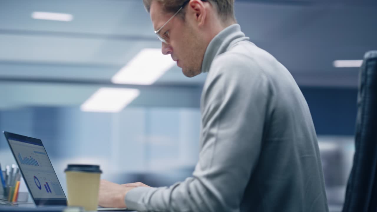 360 Degree Office: Handsome Businessman Sitting at Desk Using Laptop Computer. Digital Entrepreneur working with Big Data Digital e-Commerce Project Statistics. Tracking Shot. Camera Moving Around