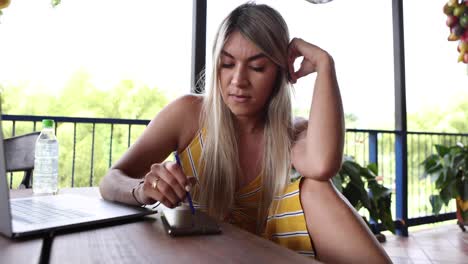 mujer usando teléfono inteligente y computadora portátil en la terraza