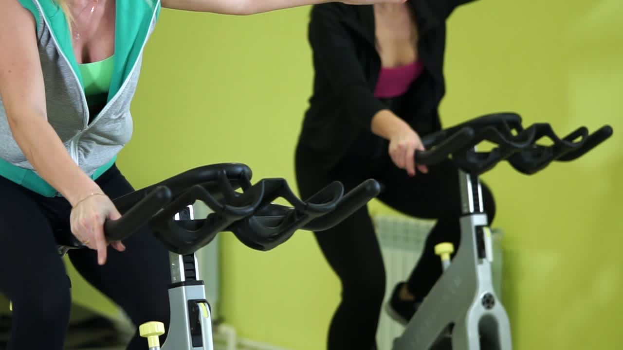 Women Exercising on Spin Bikes in a Gym