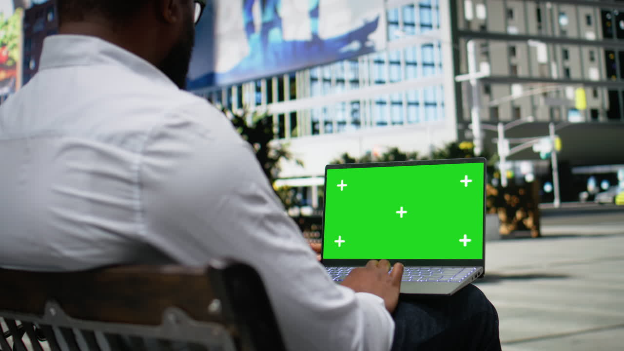 Green screen laptop with male typing emails and scrolling through online content