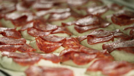 bread dough with pepperonis on top lay on a baking tray in the bakery