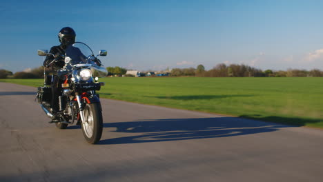 Motorista-En-Una-Motocicleta-Que-Viaja-En-Un-Camino-Rural-Fondo-Ligeramente-Borroso