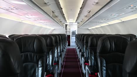 4k interior of commercial airplane cabin with black and red passenger seats.