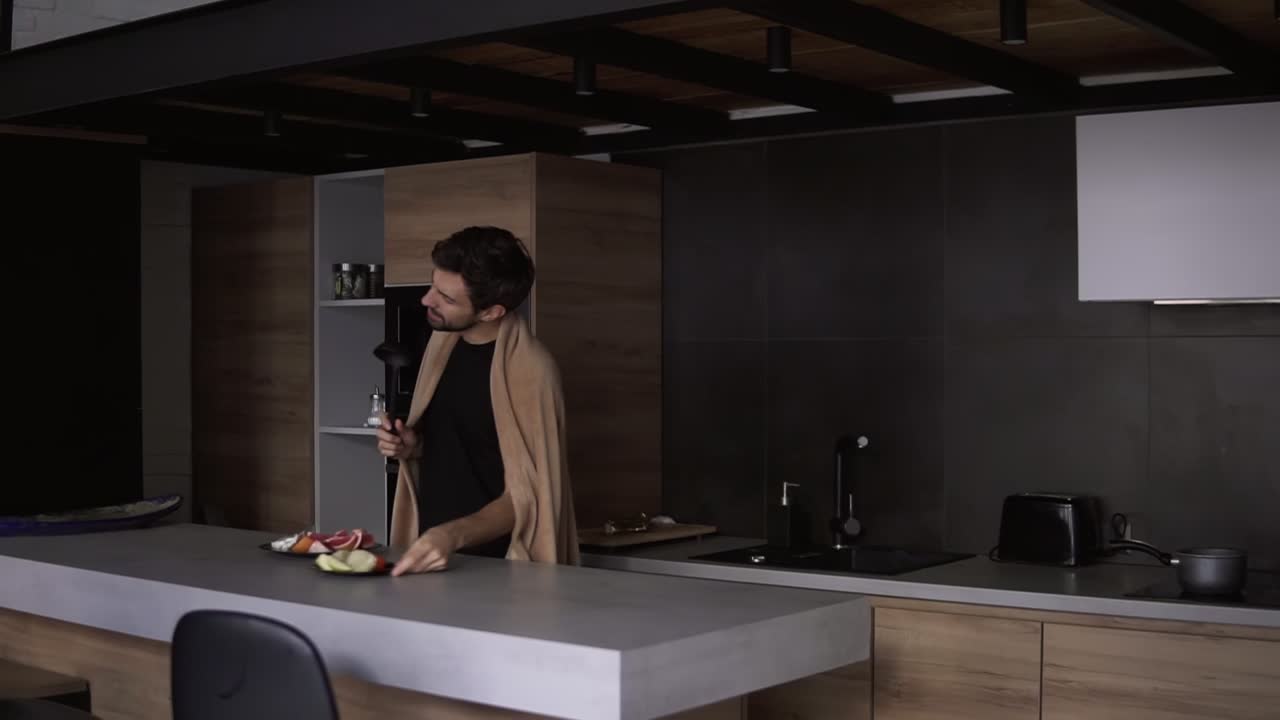 Um homem alegre coberto com uma manta xadrez com uma concha numa cozinha moderna finge cantar