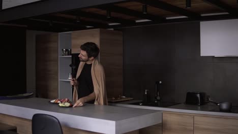 a cheerful man covered with plaid with a ladle in a modern kitchen pretends to sing