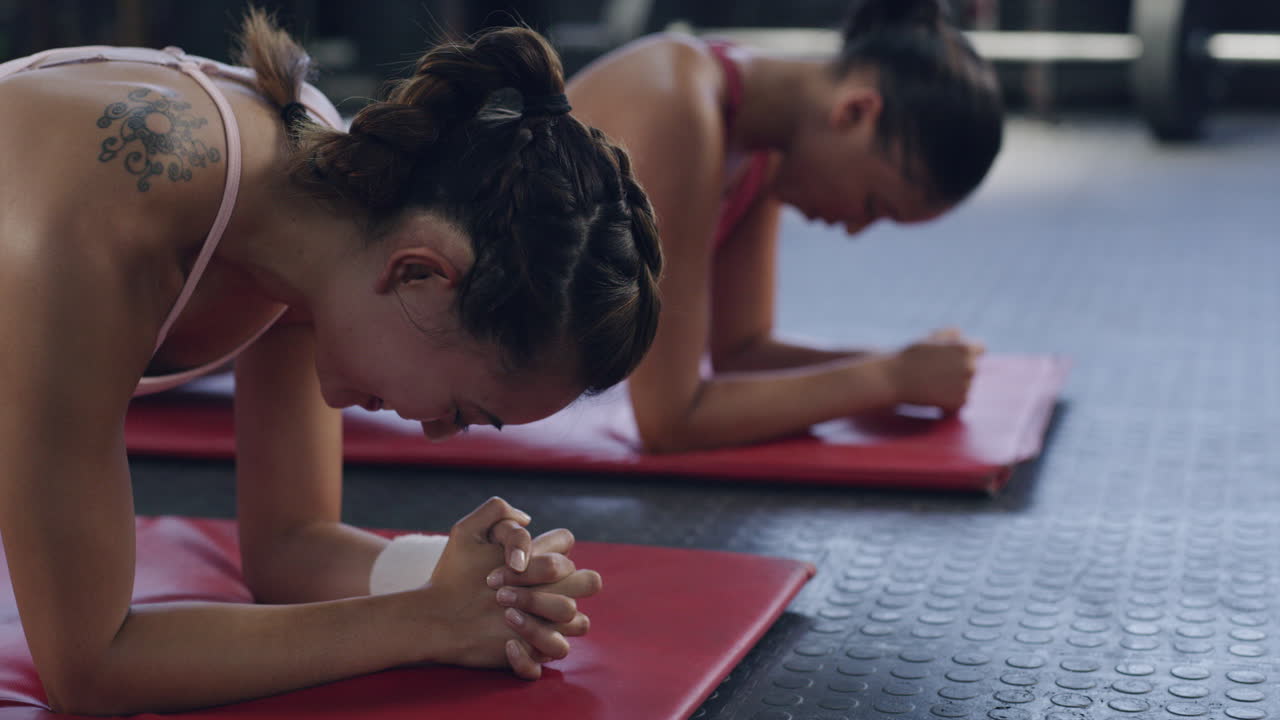 Female athletes doing the plank exercise on a mat