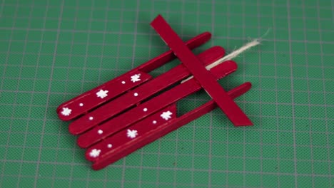 red snow sled made with popsicle sticks on a cutting mat