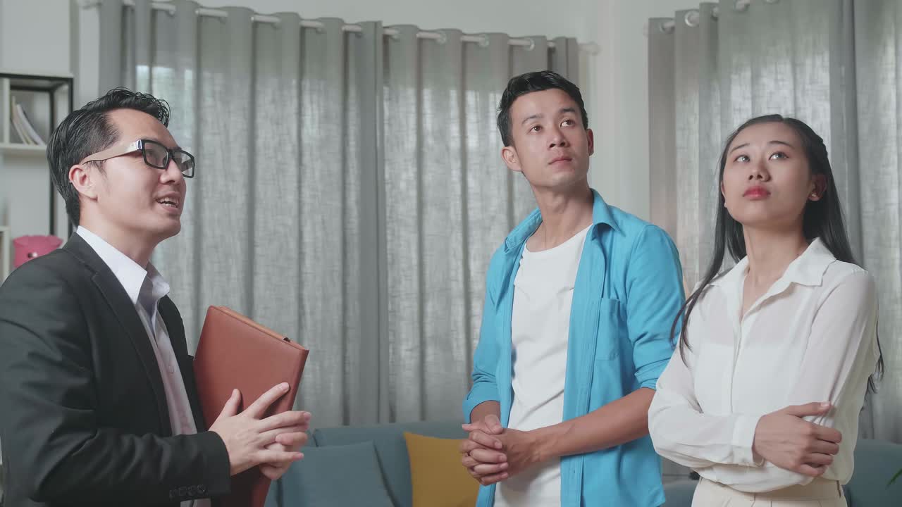 아시아 부부는 부동산 중개인이 판매 중인 집의 내부를 설명하는 것을 듣고 있습니다.