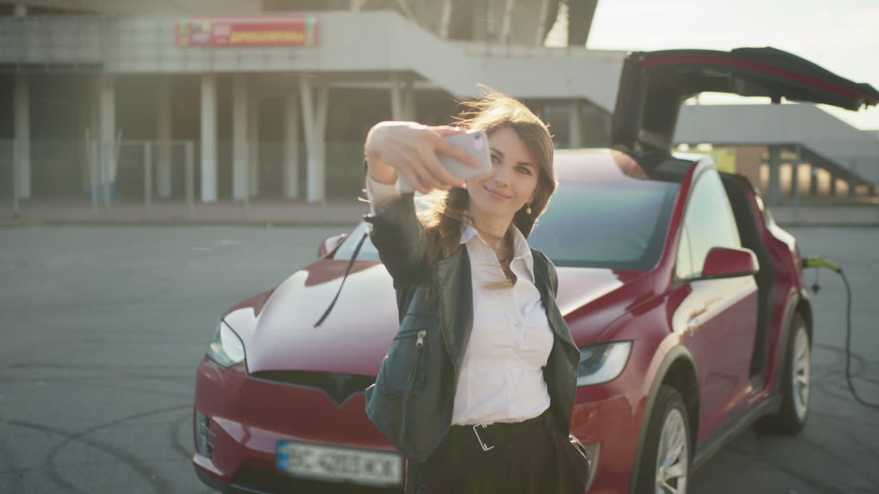 빨간 테슬라 앞에서 셀피를 찍는 여자