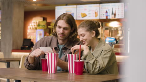 pareja hablando juntos mientras comen y beben en el snack bar del cine