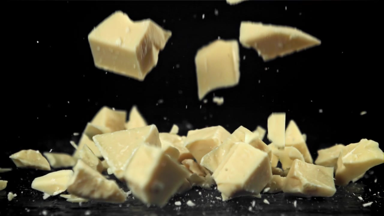 Morceaux de chocolat blanc tombant au ralenti sur fond noir