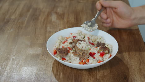 man eats rice with meat and fresh vegetables using spoon