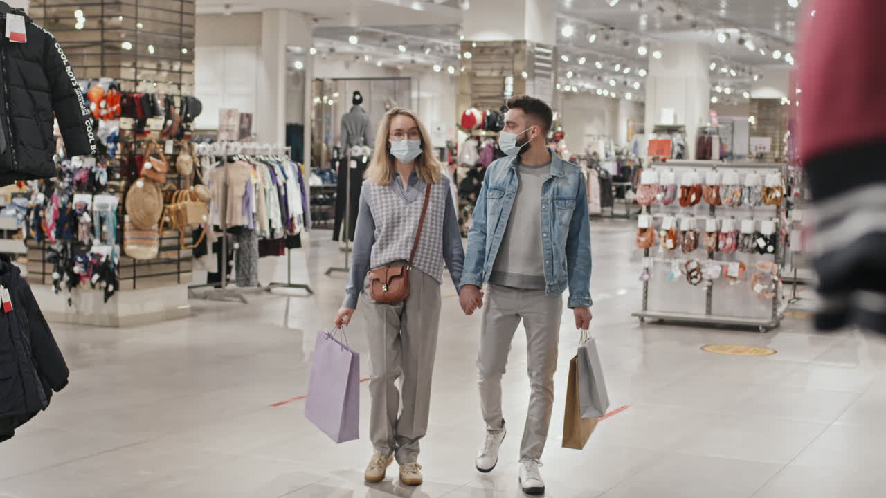 Young Couple In Face Masks Shopping At Clothing Store