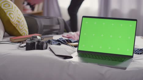 Green-Screen-Laptop-Mit-Person,-Die-Für-Den-Sommerurlaub-Zu-Hause-Einen-Koffer-Auf-Dem-Bett-Packt-1