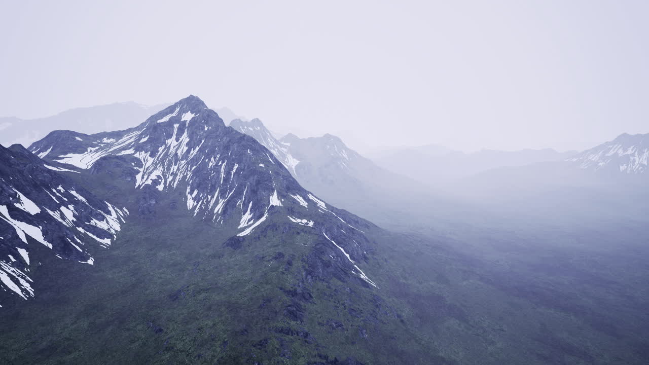 Majestic snow capped mountains rise above a lush green landscape at dawn