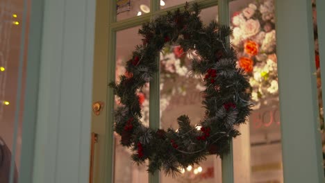 corona de bayas rojas de navidad colgando de una puerta