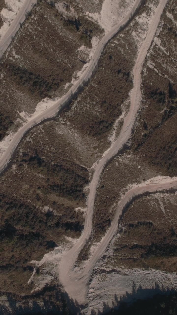 Drone footage of a winding dirt road with sharp switchbacks on a steep mountain slope at Katu-Yaryk Pass, Altai Republic, Russia, remote travel landscape
