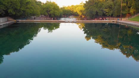 Quick-pan-up-from-barton-springs-pool,-down-barton-creek,-revealing-downtown-Austin-Texas