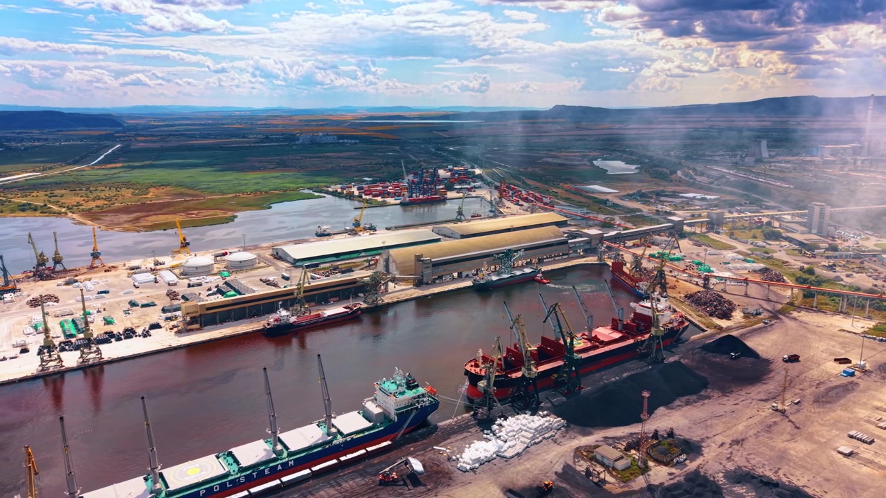 Varna, Bulgaria, 3 de junio de 2026: Buques de carga atracados en una terminal portuaria industrial. Grandes buques comerciales bordean el puerto mientras las grúas manipulan la carga junto a pilas de carbón y almacenes.