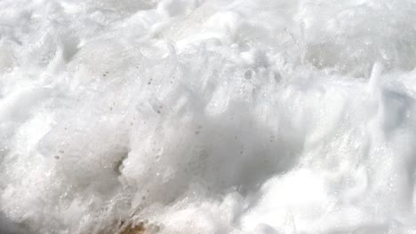 primer plano de las olas espumosas que chocan contra las rocas en la isla de corfú