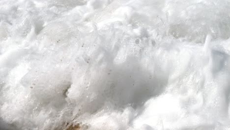 close-up of foamy waves crashing against rocks on corfu island